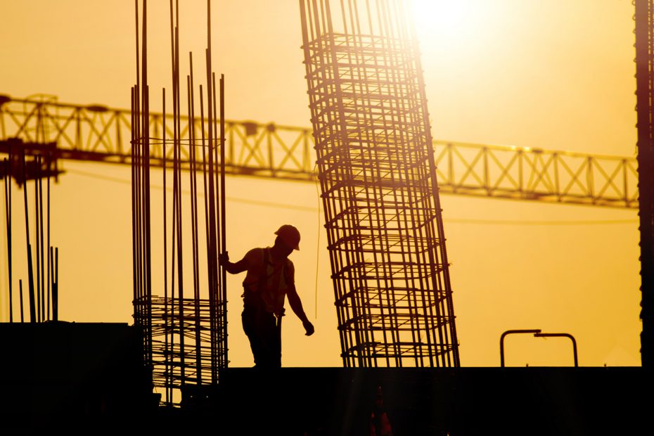 silhouette di un lavoratore in un cantiere con cielo arancione