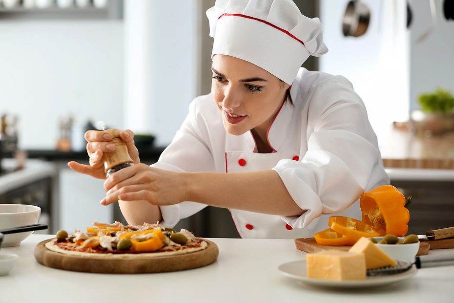 Young female chef cooking tasty pizza in kitchen