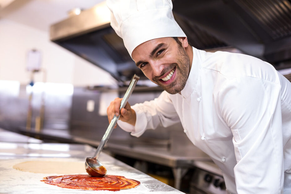 cuoco spalma la passata di pomodoro sulla pasta della pizza