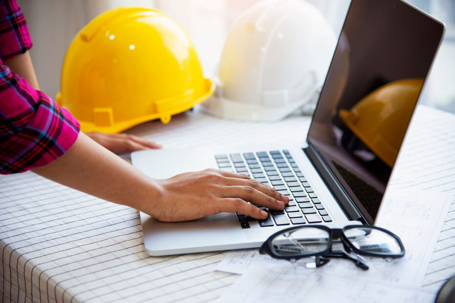 Workers and manager in safety helmets working with documents at